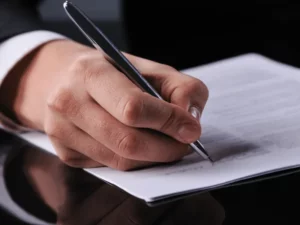 Main tenant un stylo pour la signature d'un contrat de prévoyance obsèques.