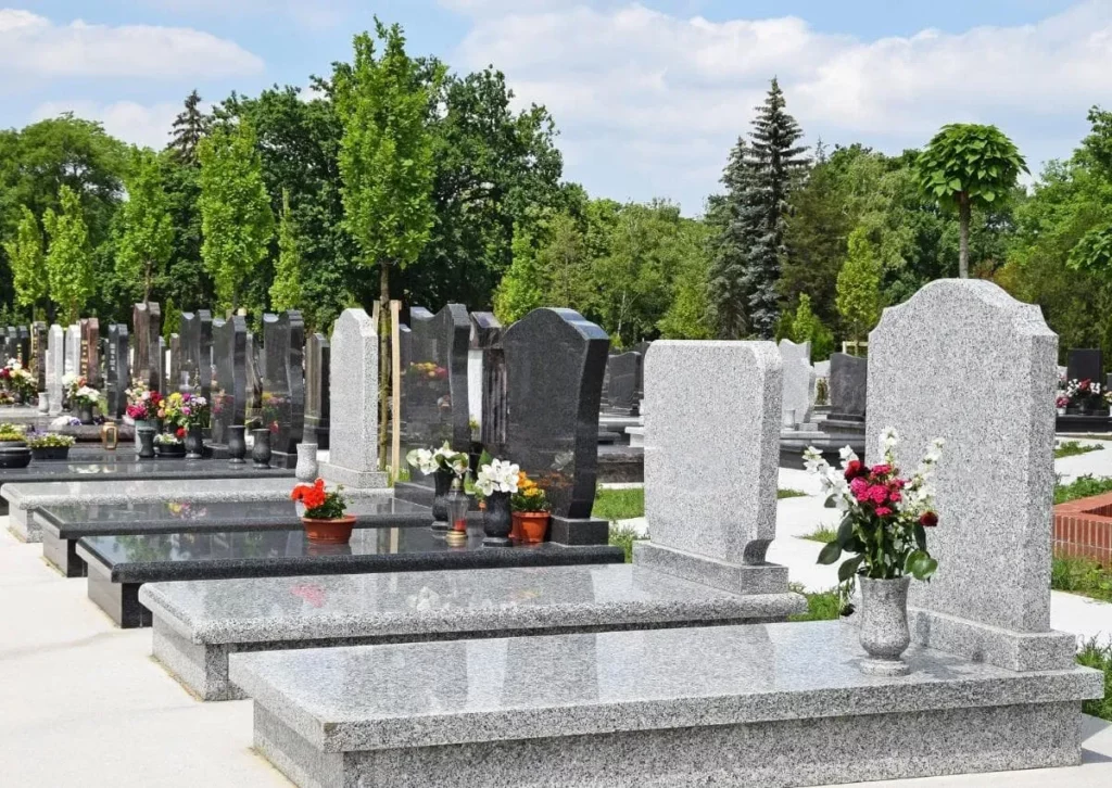 Alignement de monuments funéraires en granit dans un cimetière aménagé.