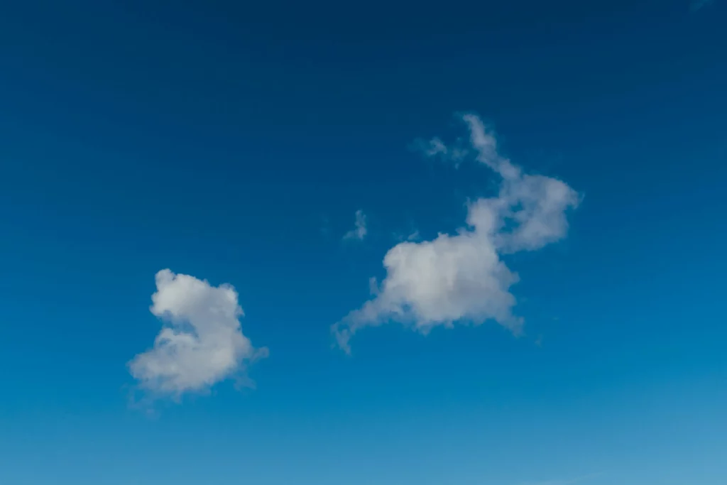 Quelques petits nuages blancs isolés dans un ciel bleu profond.
