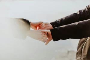 Gros plan sur deux personnes se tenant la main en signe de soutien.