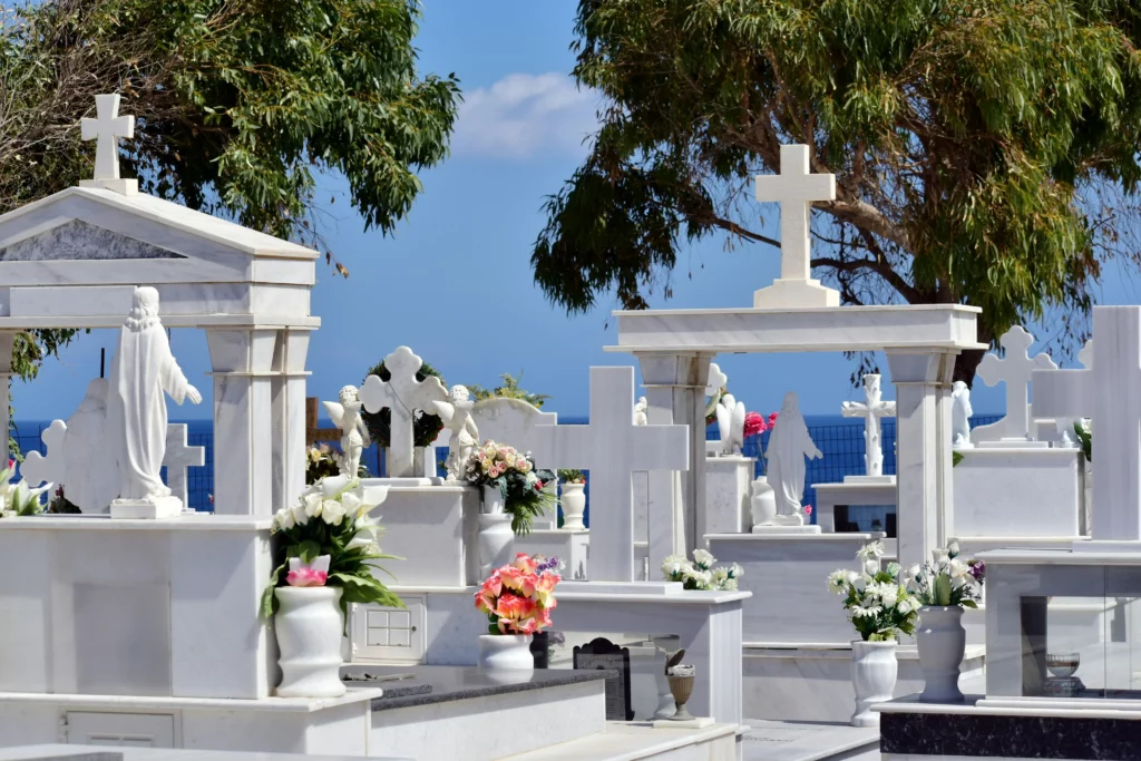 Cimetière marin avec tombes, croix et statues en marbre blanc.