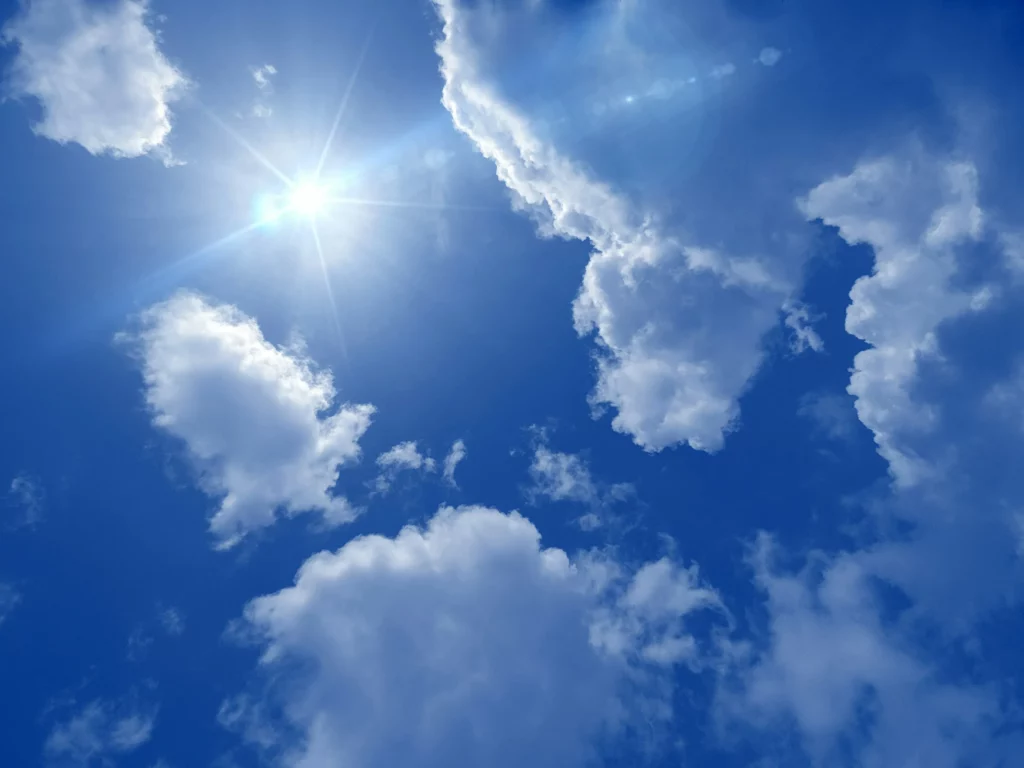 Ciel bleu ensoleillé parsemé de nuages blancs lumineux.