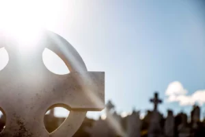Croix celtique en pierre éclairée par un rayon de soleil au cimetière.