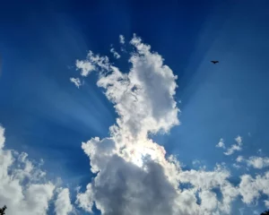 Rayons de soleil perçant à travers de grands nuages blancs dans le ciel.